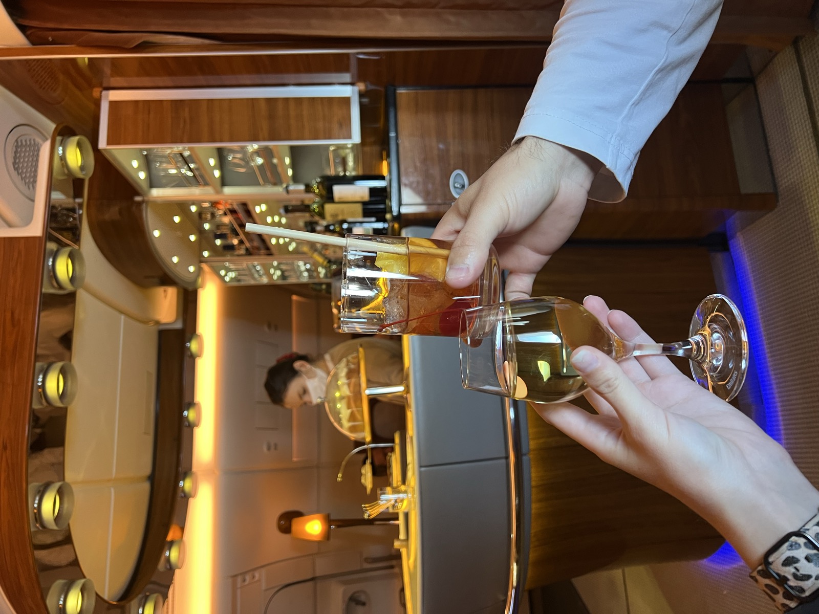 Mike and Christie holding up their drinks at the warmly lit Emirates onboard bar
